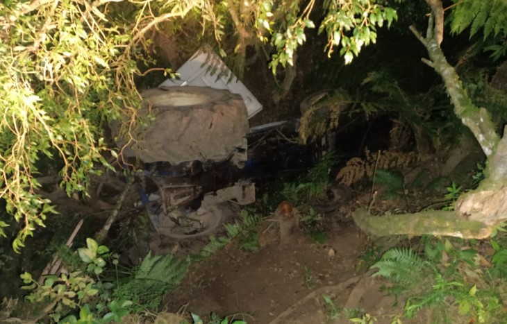 Mulher fica presa embaixo de trator tombado em ribanceira