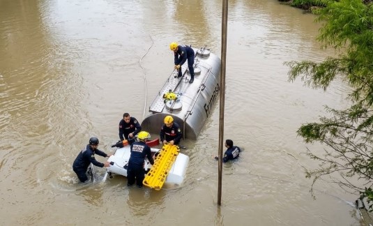 Caminhoneiro fica preso na cabine após caminhão com 3 mil litros de leite cair em rio